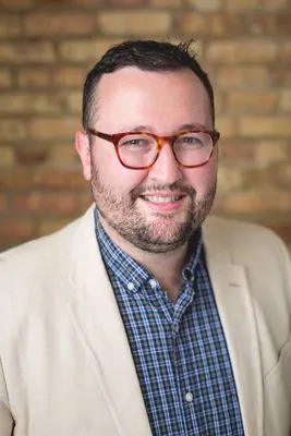 Male performer headshot with natural backdrop